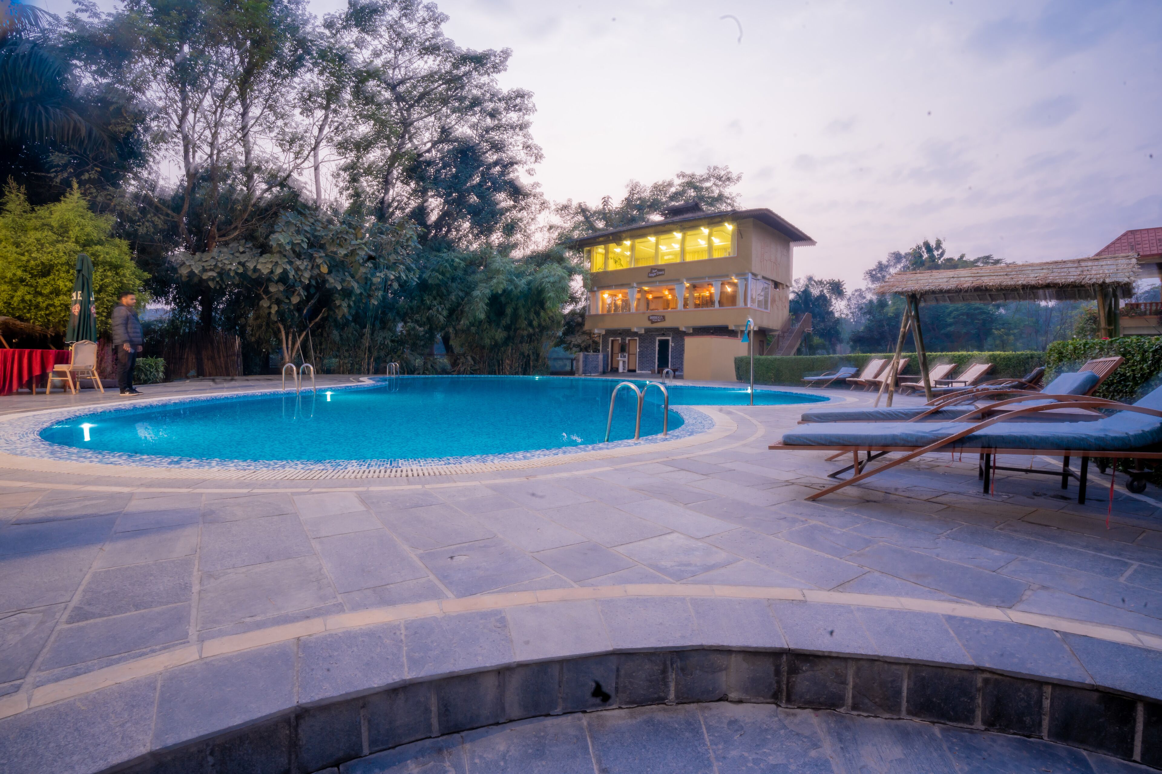 A swimming pool with lounge chairs and a building with multiple floors.