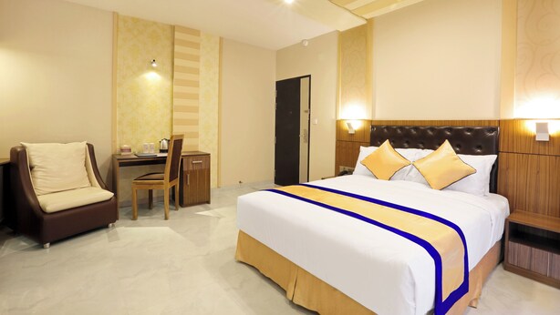 Une chambre d’hôtel avec un grand lit, un bureau avec une chaise et une petite table.