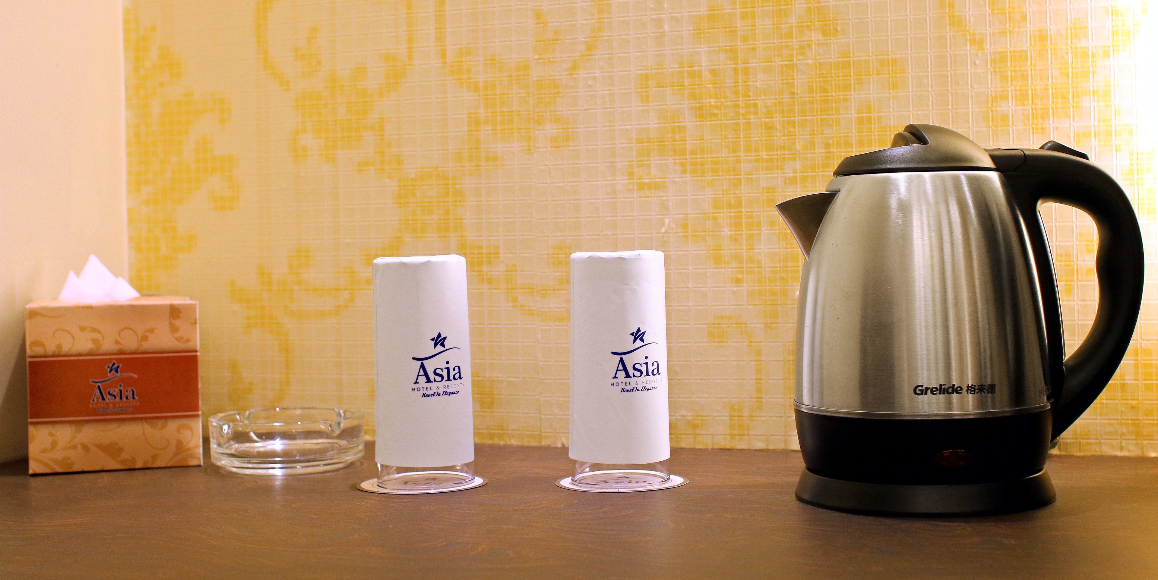 A table with a tissue box, two candles, and a kettle.
