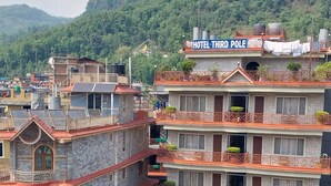 Un hôtel à plusieurs étages doté de balcons, une enseigne indiquant « Hôtel Pôle Nord », et une vue sur les bâtiments et les collines environnants.