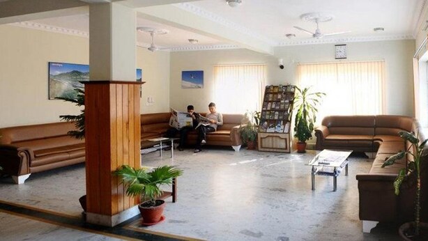 Un hall d’entrée spacieux, doté de canapés en cuir, d’une table basse et de plantes en pot.