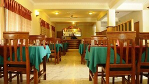 Un restaurant avec des chaises en bois et des nappes vertes disposées en rangées.