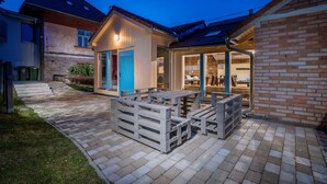 A patio area with a wooden table and benches, a blue door, and a brick wall. - Apartments Ceresnovy Sad (Mengusovce)