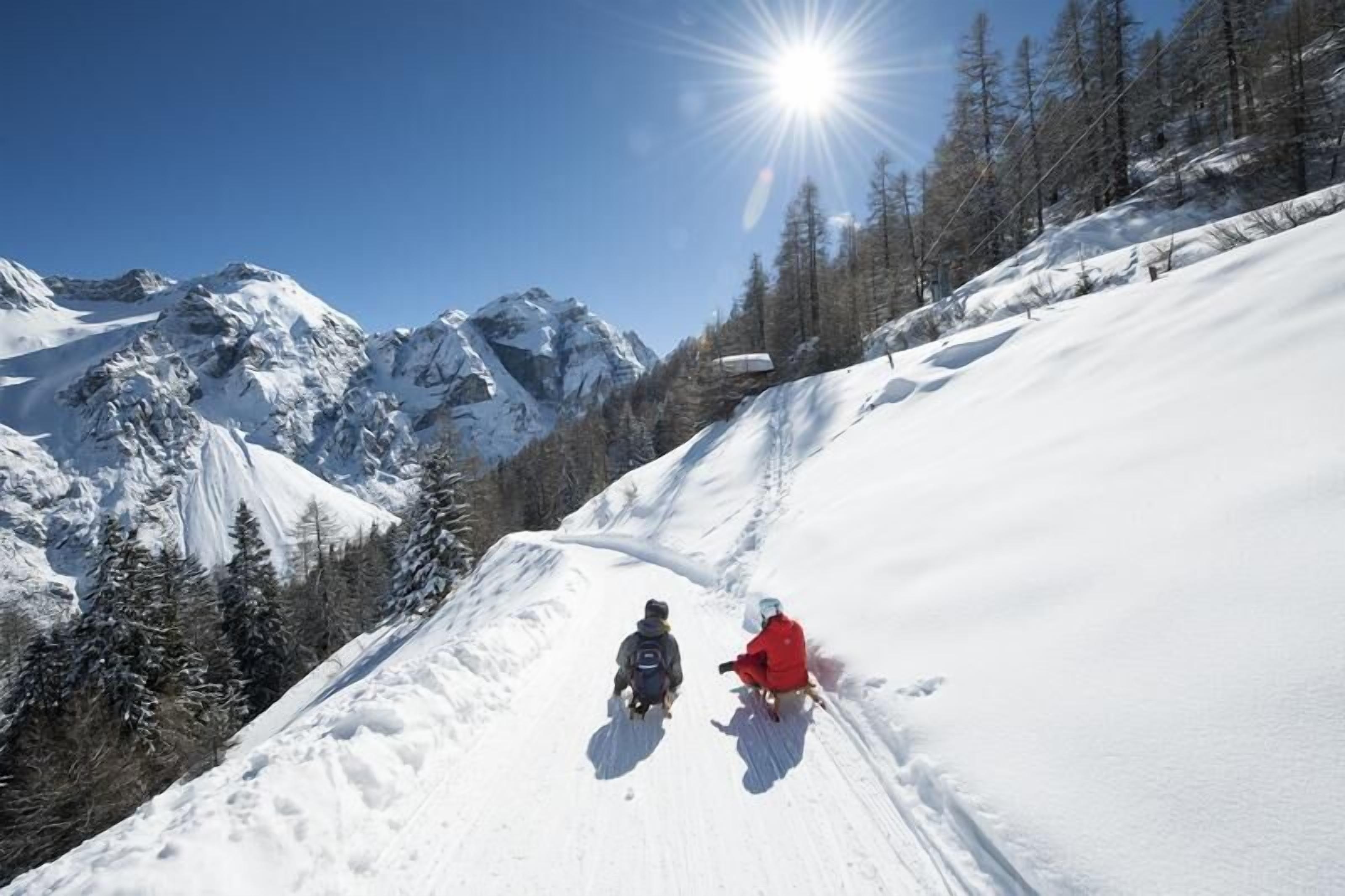 A snowy mountain slope with two skiers descending.