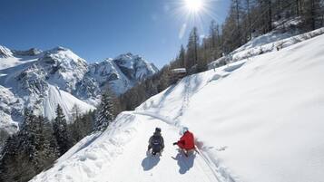 A snowy mountain slope with two skiers descending.