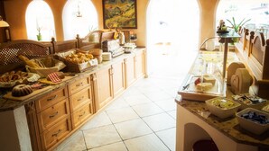 A spacious kitchen with wooden cabinets, a marble countertop, and a view through arched windows. - Hotel Augarten (Neustift Im Stubaital)