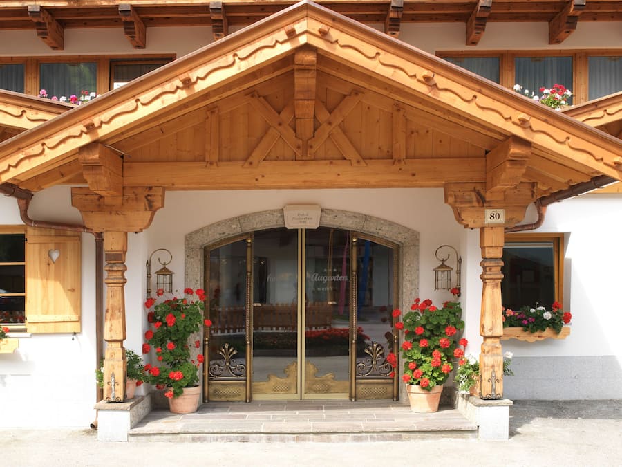Un edificio in legno con un'ampia entrata, piante in vaso e un cartello sopra la porta.