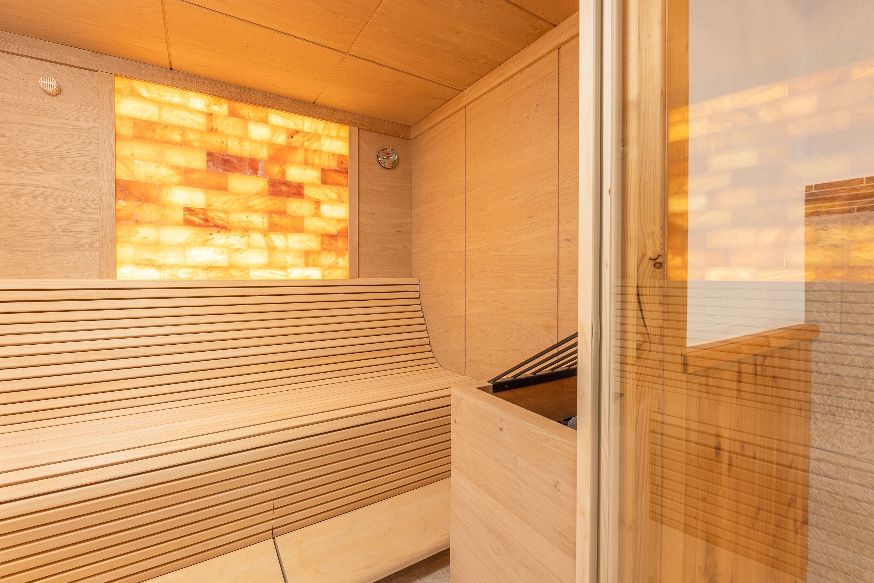 A sauna with wooden benches and a glass wall.