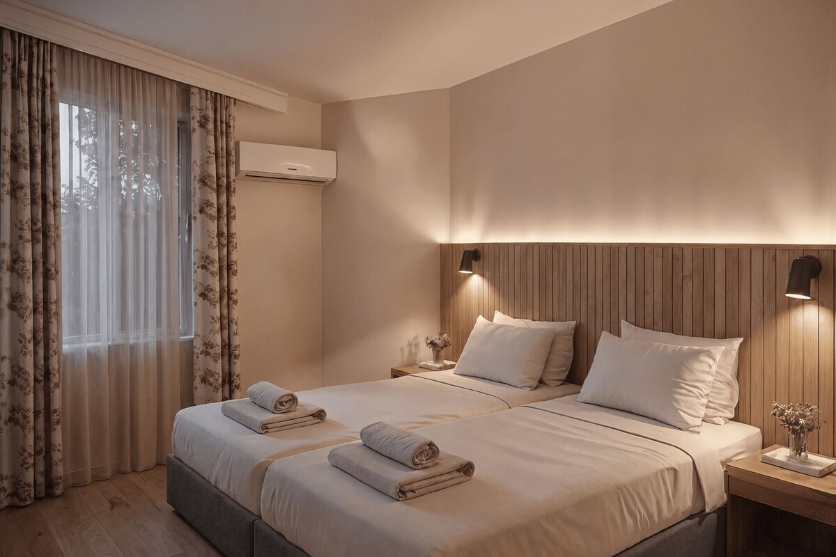 A hotel room with two beds, a wooden headboard, a nightstand, a wall-mounted air conditioner, and a window with curtains.