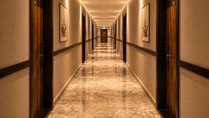 A hotel hallway with a marble floor, wooden doors, and framed artwork on the walls. - Bella Rose Apart Hotel (Alanya)