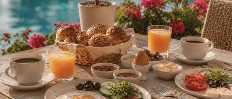 A breakfast setting with a pool view, including croissants, eggs, and fresh fruit.