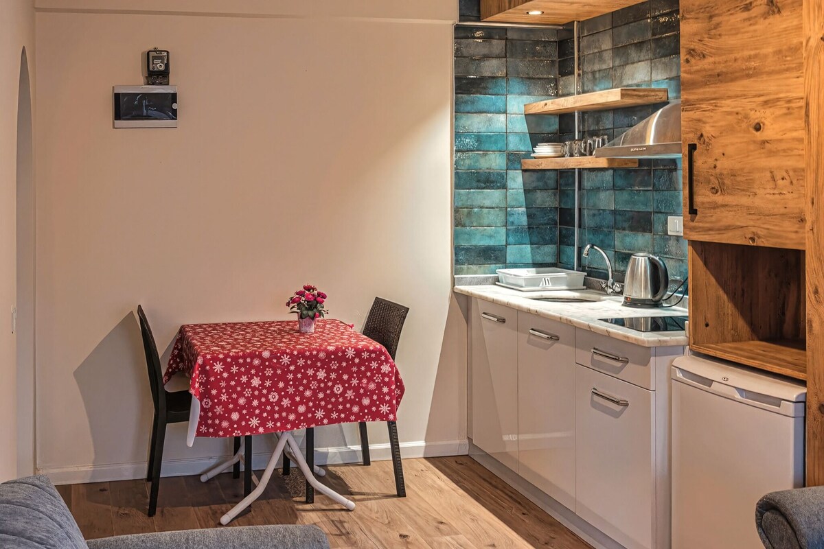 A compact kitchen with a dining table, chairs, and a small refrigerator.