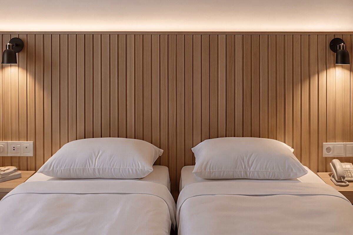 A hotel room with two beds, wooden paneling on the walls, bedside lamps, and a telephone on the nightstand.