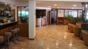 A spacious lobby with a bar area, seating, and a reception desk. - Hotel Smeraldo (Lignano Sabbiadoro)