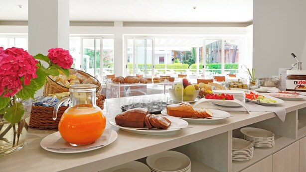 A breakfast buffet with various food items and a glass pitcher of orange juice. - Hotel Smeraldo (Lignano Sabbiadoro)