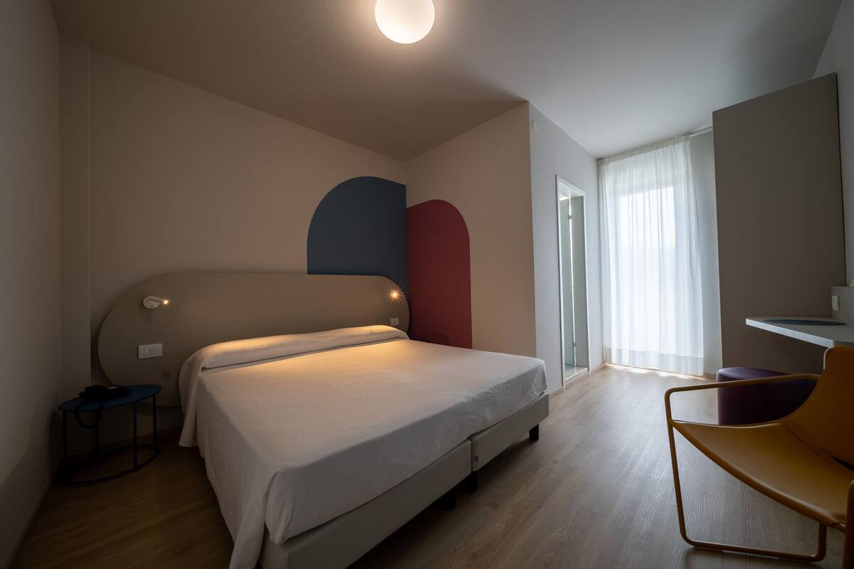 Un dormitorio moderno con una cama, un escritorio y una silla.