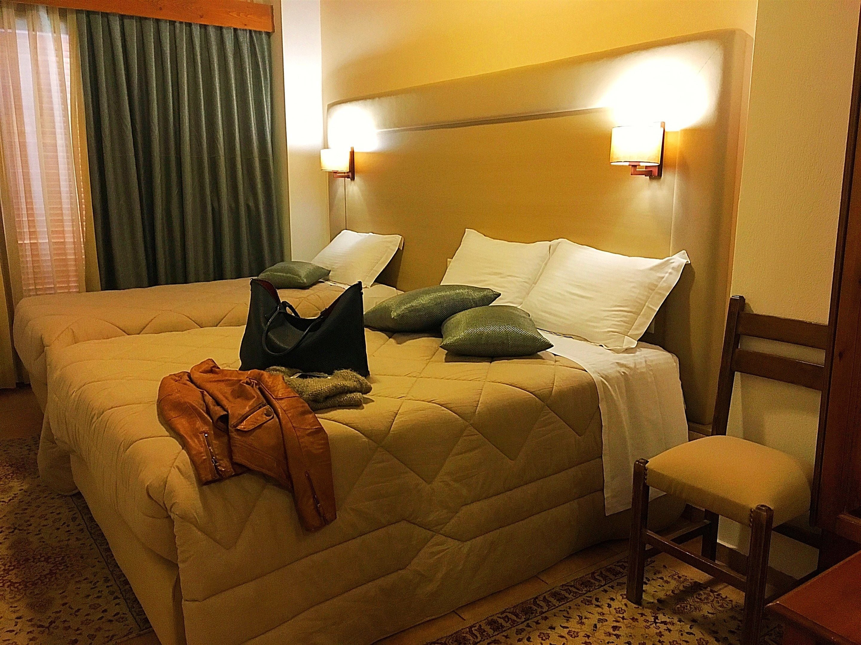 A hotel room with a large bed, a chair, and a nightstand.