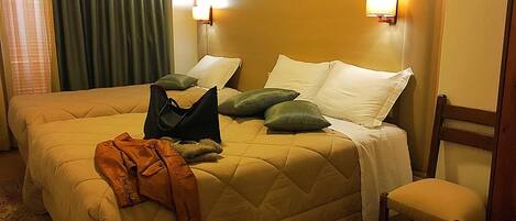 A hotel room with a large bed, a chair, and a nightstand.