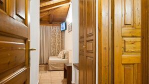 A wooden door leading to a room with a bed, curtains, and a television on the wall. - Pan Hotel (Delphi)