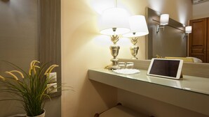 A bathroom with a glass countertop, two wall-mounted lamps, a potted plant, and a tablet on the counter. - Pan Hotel (Delphi)