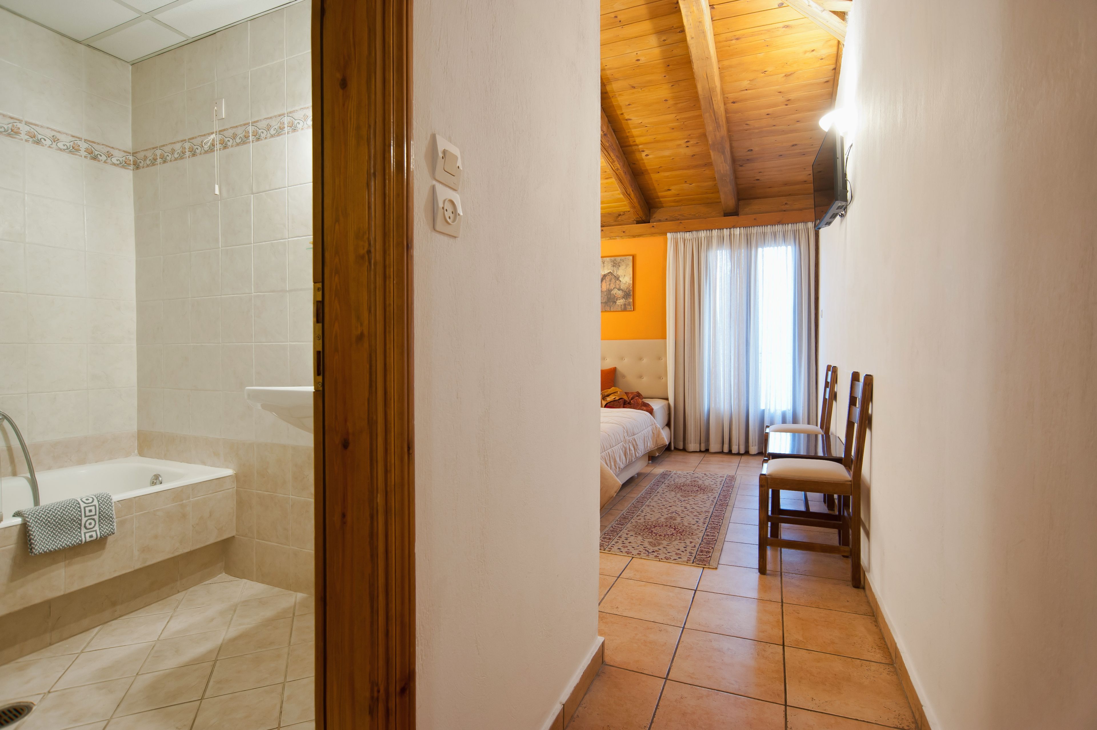 A bathroom with a bathtub and a shower, a bedroom with a bed and a window, and a dining area with chairs and a table.