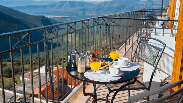 A balcony with a table set for breakfast, overlooking a mountainous landscape. - Pan Hotel (Delphi)