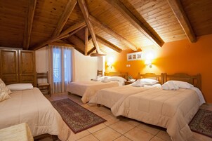 Habitación de hotel con dos camas, vigas de madera en el techo, una mesita de noche con lámpara y una ventana con cortinas.