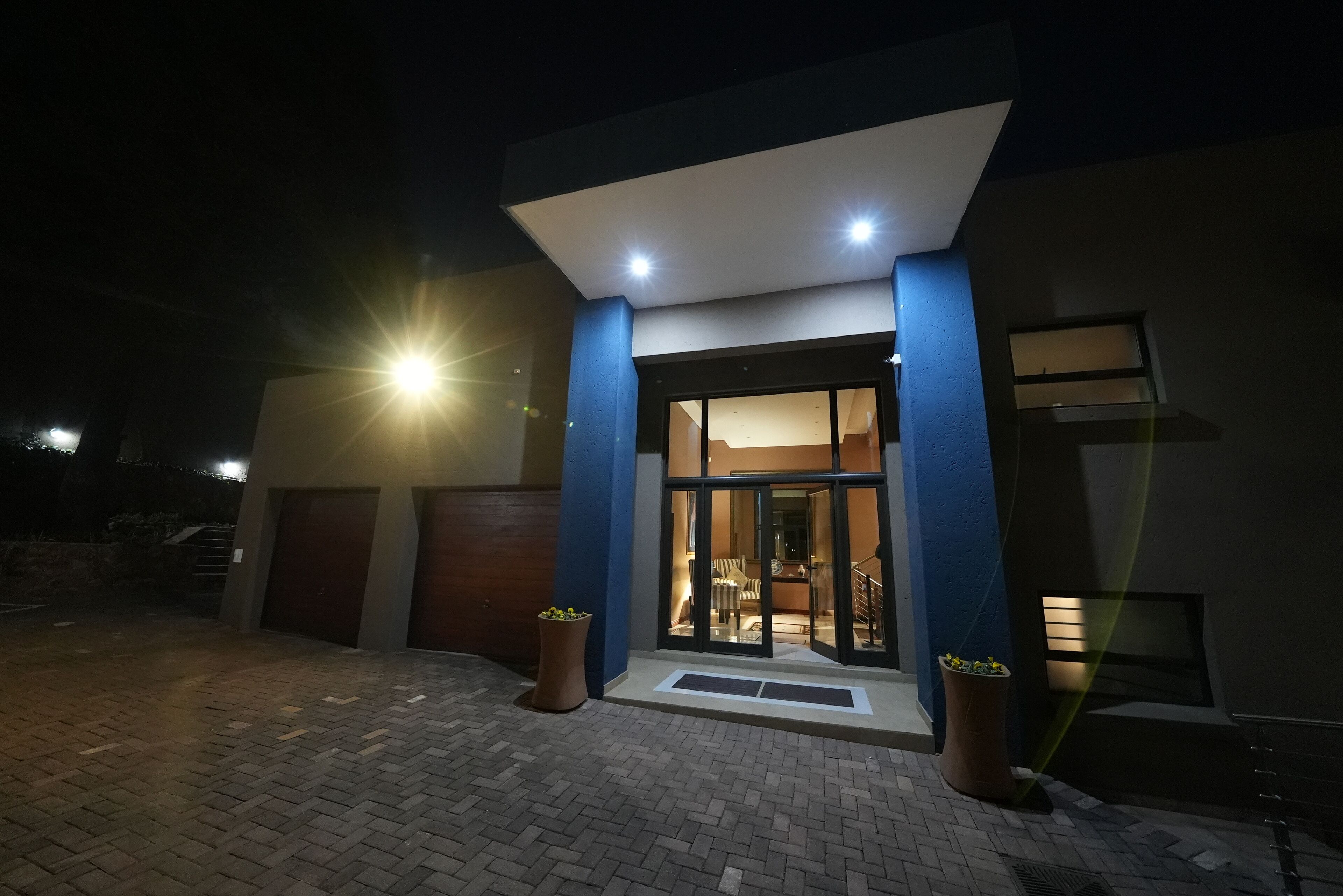 A modern building with a well-lit entrance, large windows, and a paved driveway.