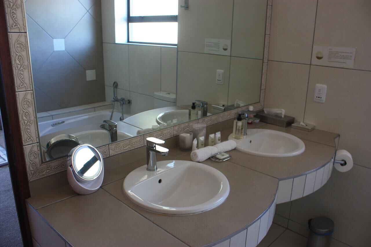 Un baño con dos lavamanos, un espejo y un inodoro.