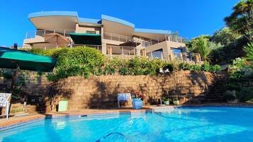 Una piscina al aire libre, sombrillas, sillones reclinables de piscina