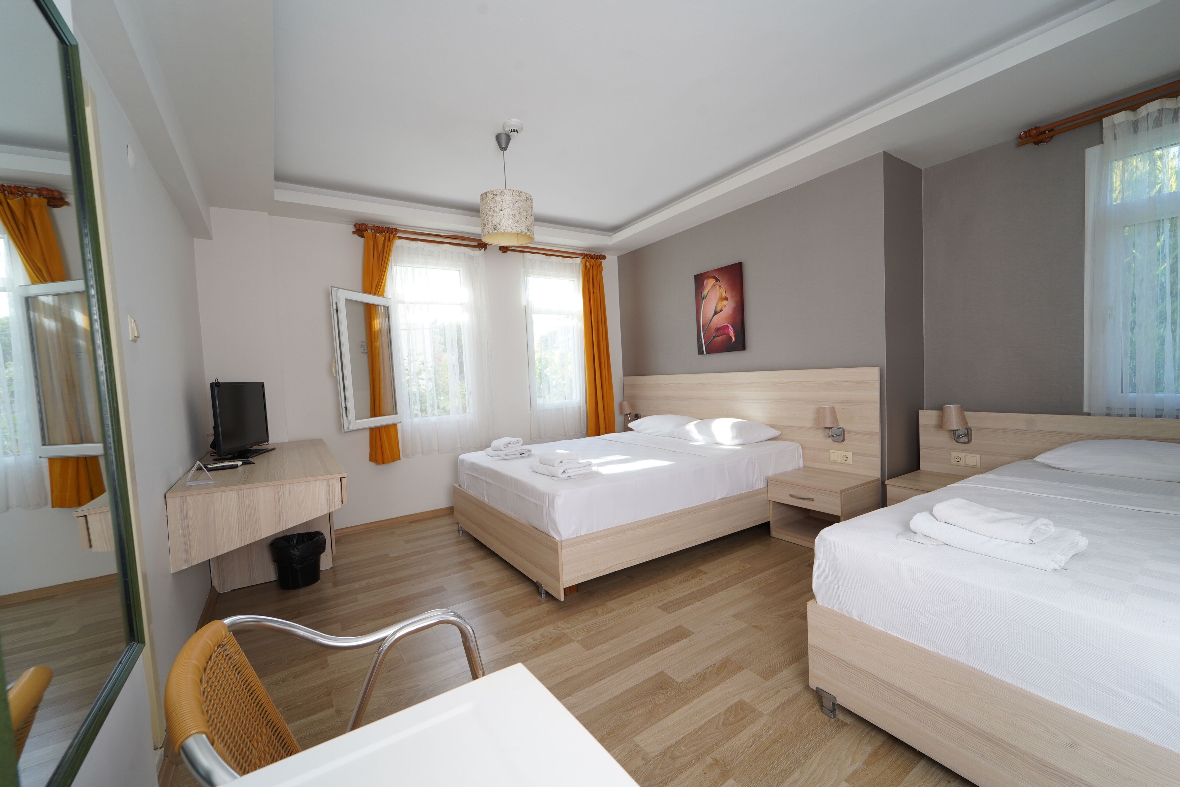 A hotel room with a bed, a desk, a chair, a television, and a painting on the wall.
