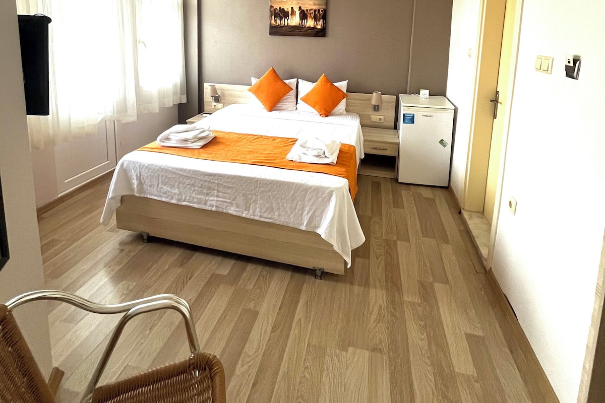 Una habitación de hotel con una cama, una silla, un escritorio y un refrigerador pequeño.