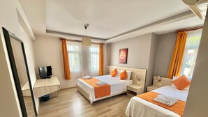 A hotel room with two beds, a desk, and a TV. - Limon Pansiyon (Foça)