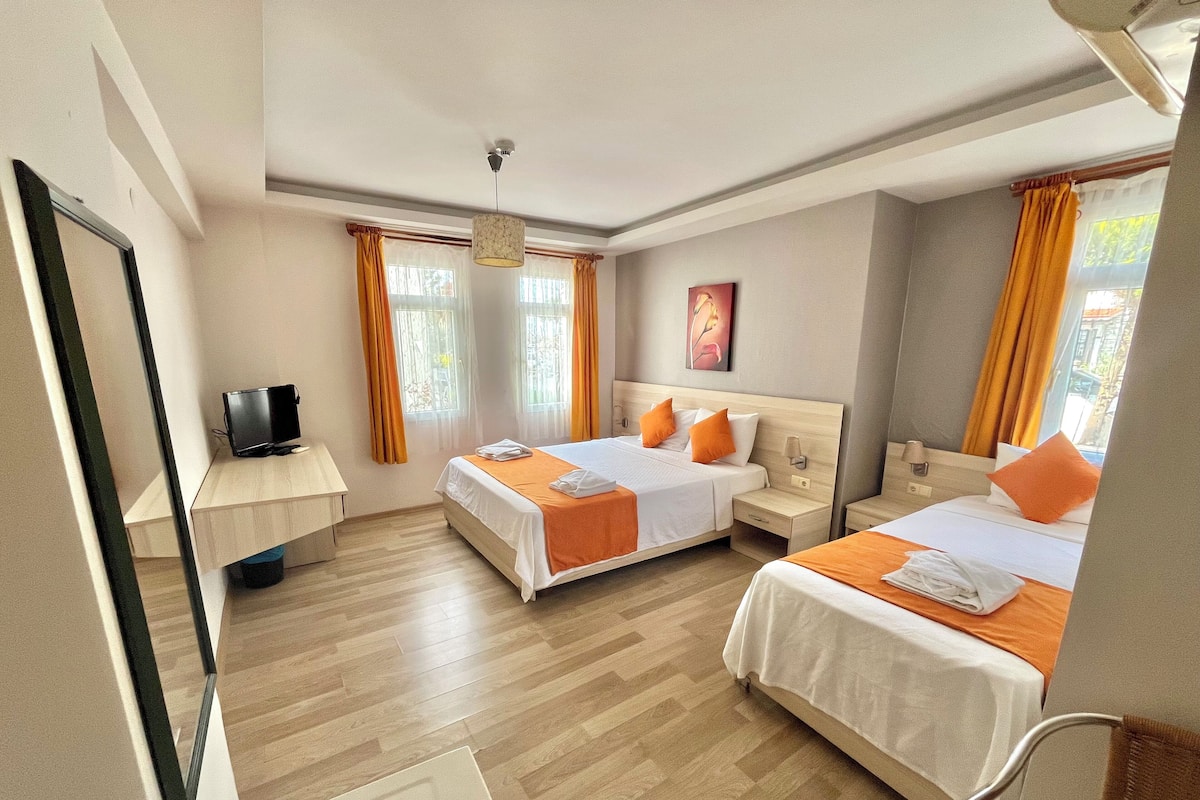 Habitación de hotel con dos camas, un escritorio y un televisor.