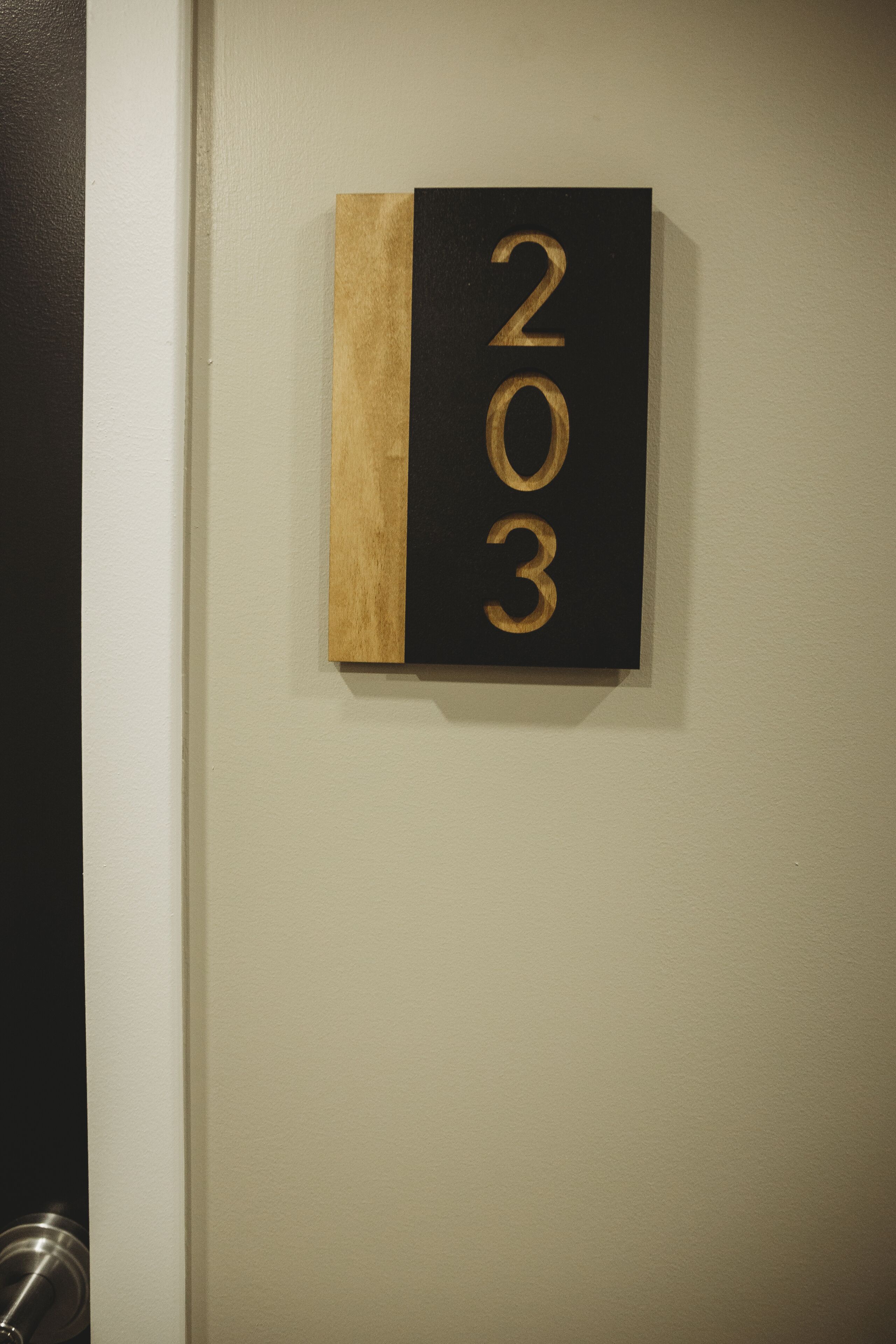 A wall-mounted number plate with the numbers 203.