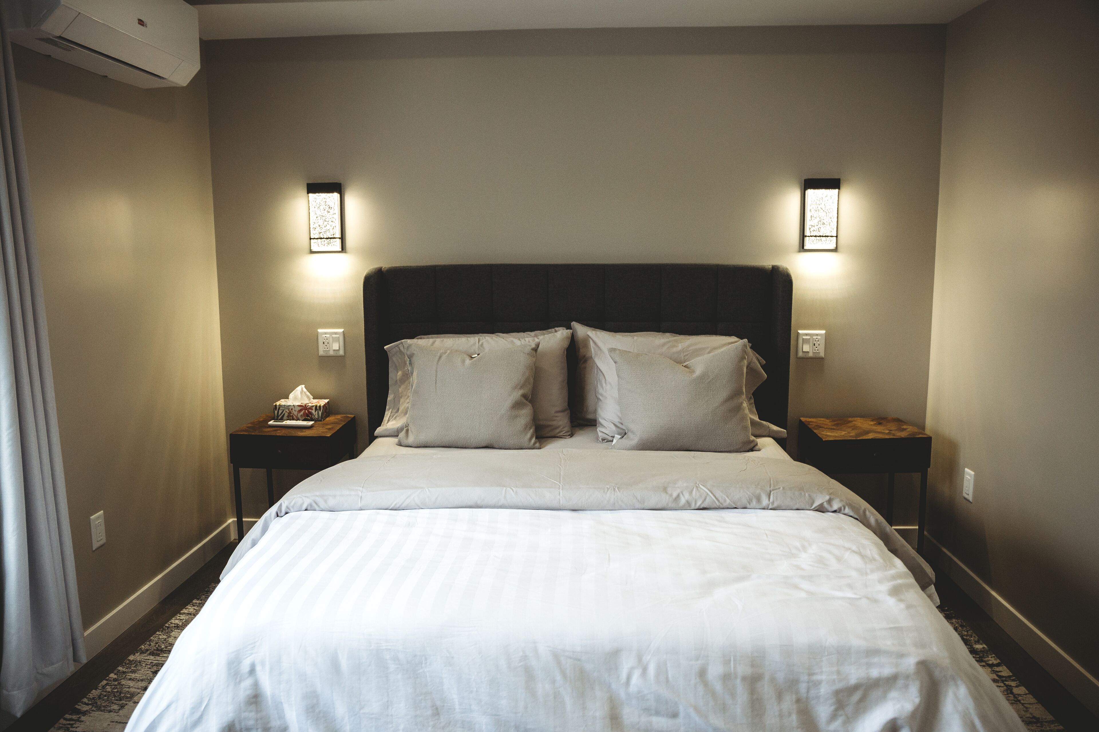 Une chambre d’hôtel avec un grand lit, deux tables de chevet et des lampes de lecture fixées au mur.