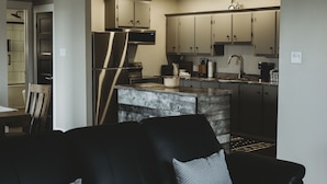 A modern kitchen with stainless steel appliances, wooden cabinets, and a central island. - Riverside Suites (Grand Falls - Windsor)