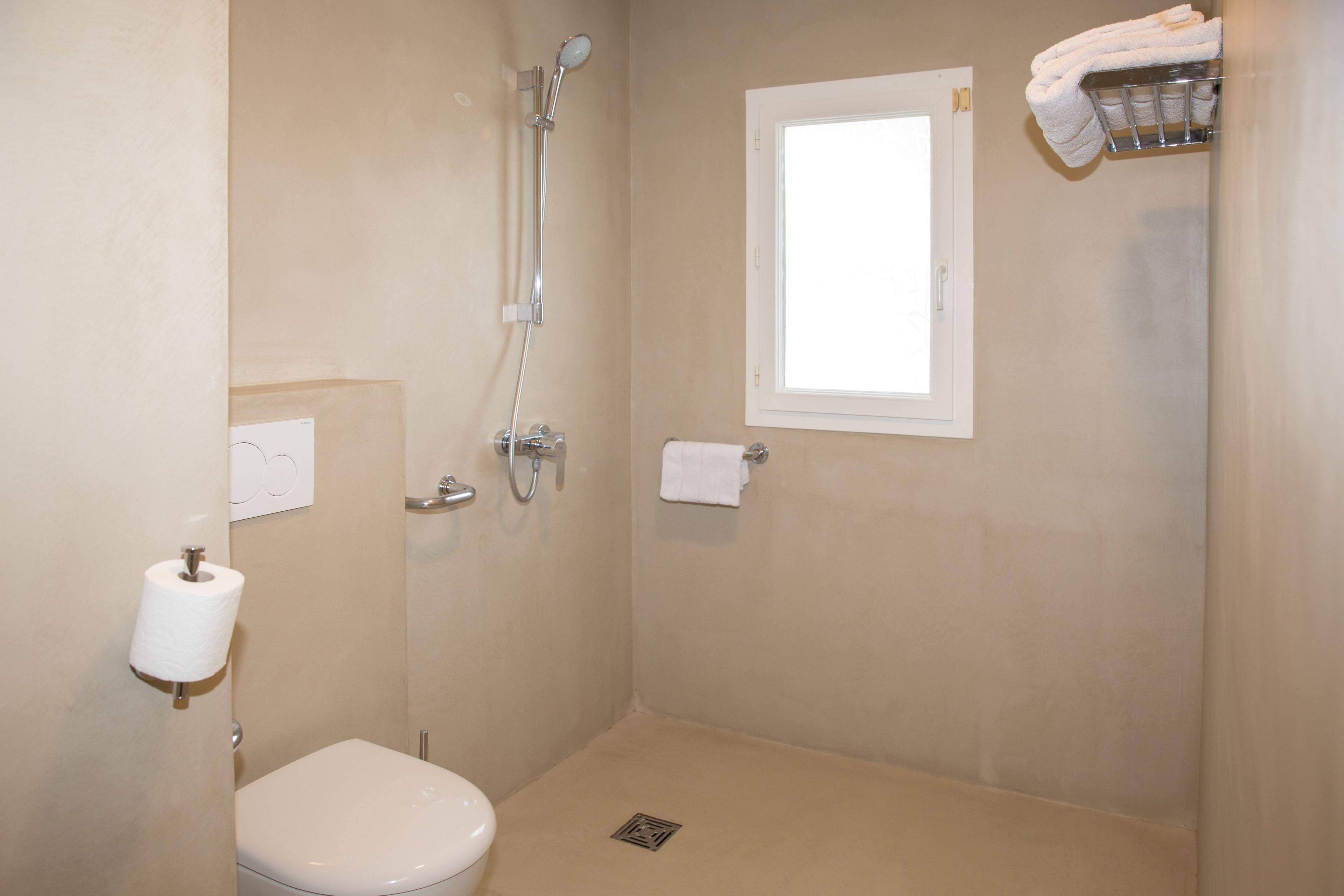 Een kleine, schone badkamer met toilet, douche en raam.