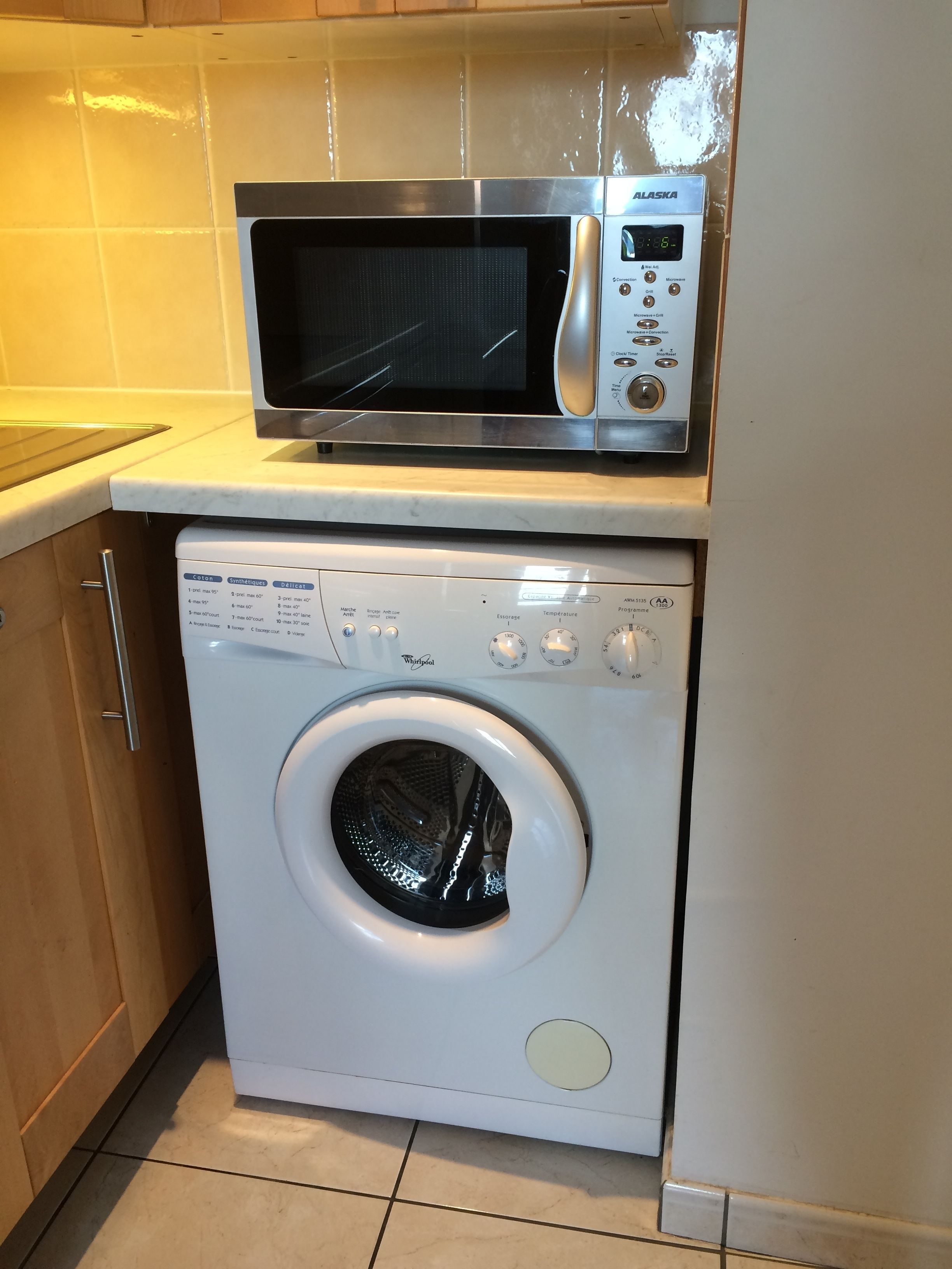 A compact kitchen with a microwave and a front-loading washing machine.