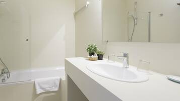Un baño moderno con lavamanos, espejo y ducha blancos.
