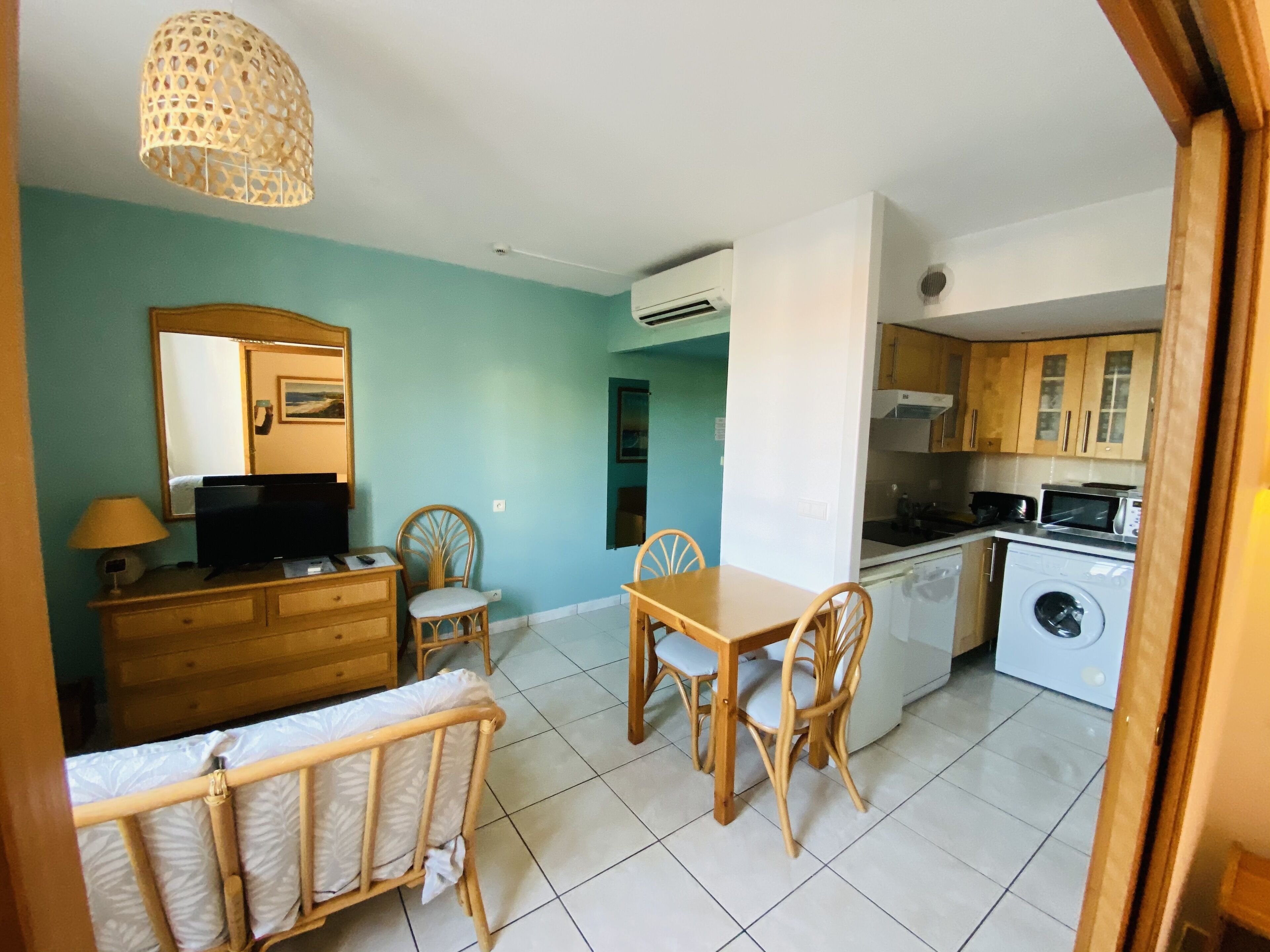 Un espacio habitable compacto con comedor, kitchenette y un dormitorio pequeño.
