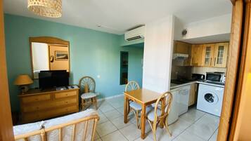 Un espacio habitable compacto con comedor, kitchenette y un dormitorio pequeño.