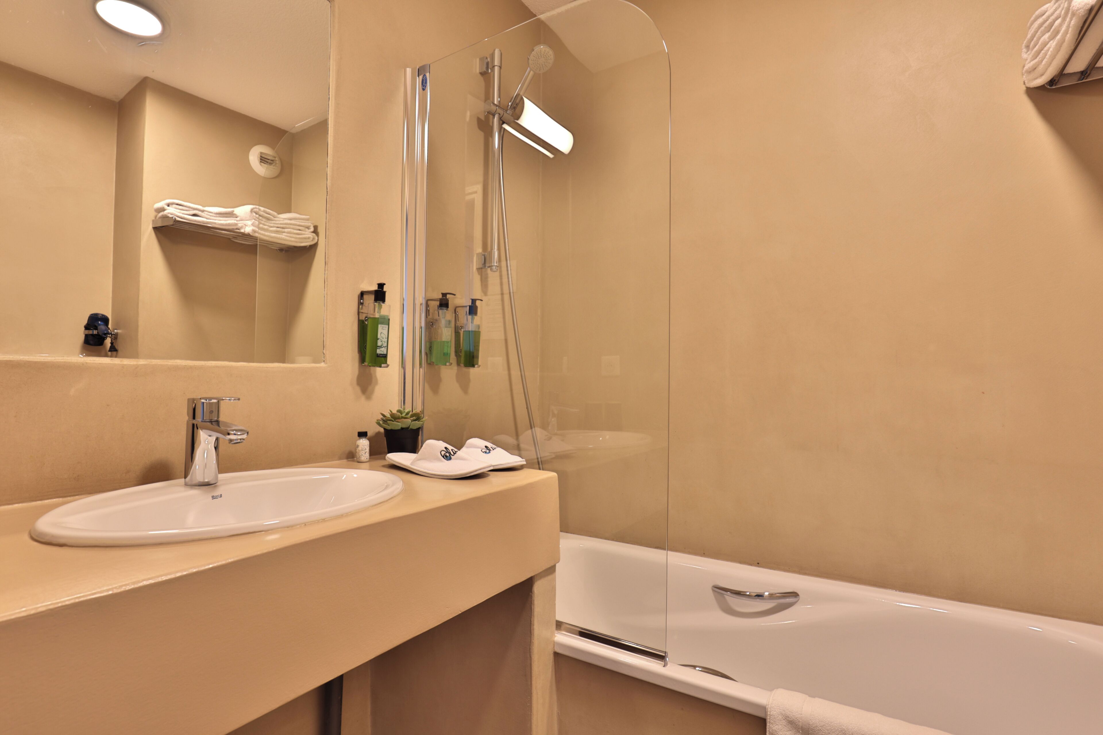 Un baño con lavamanos, espejo, ducha y bañera.