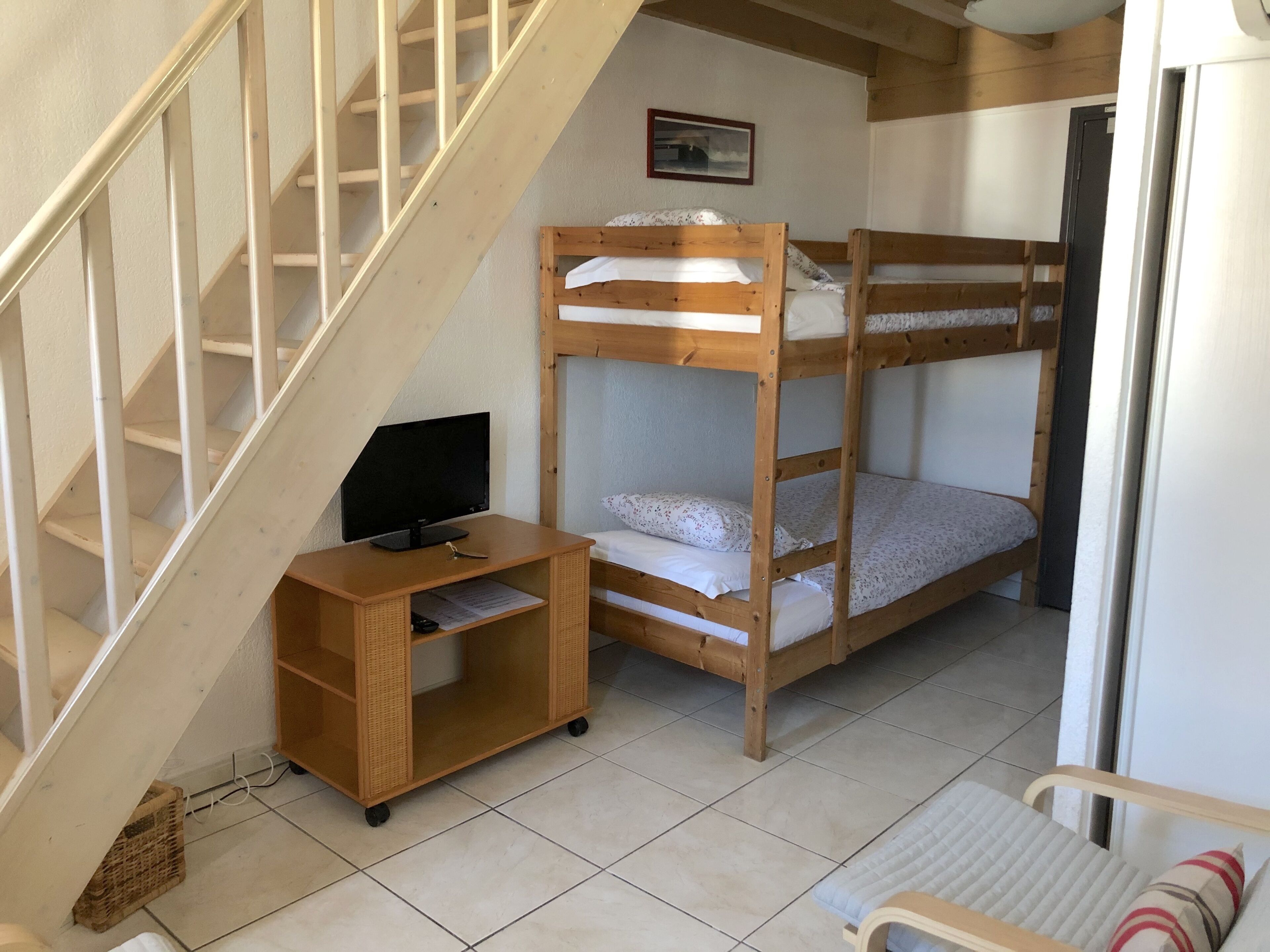 Una habitación con literas, un escritorio con computadora y una silla.