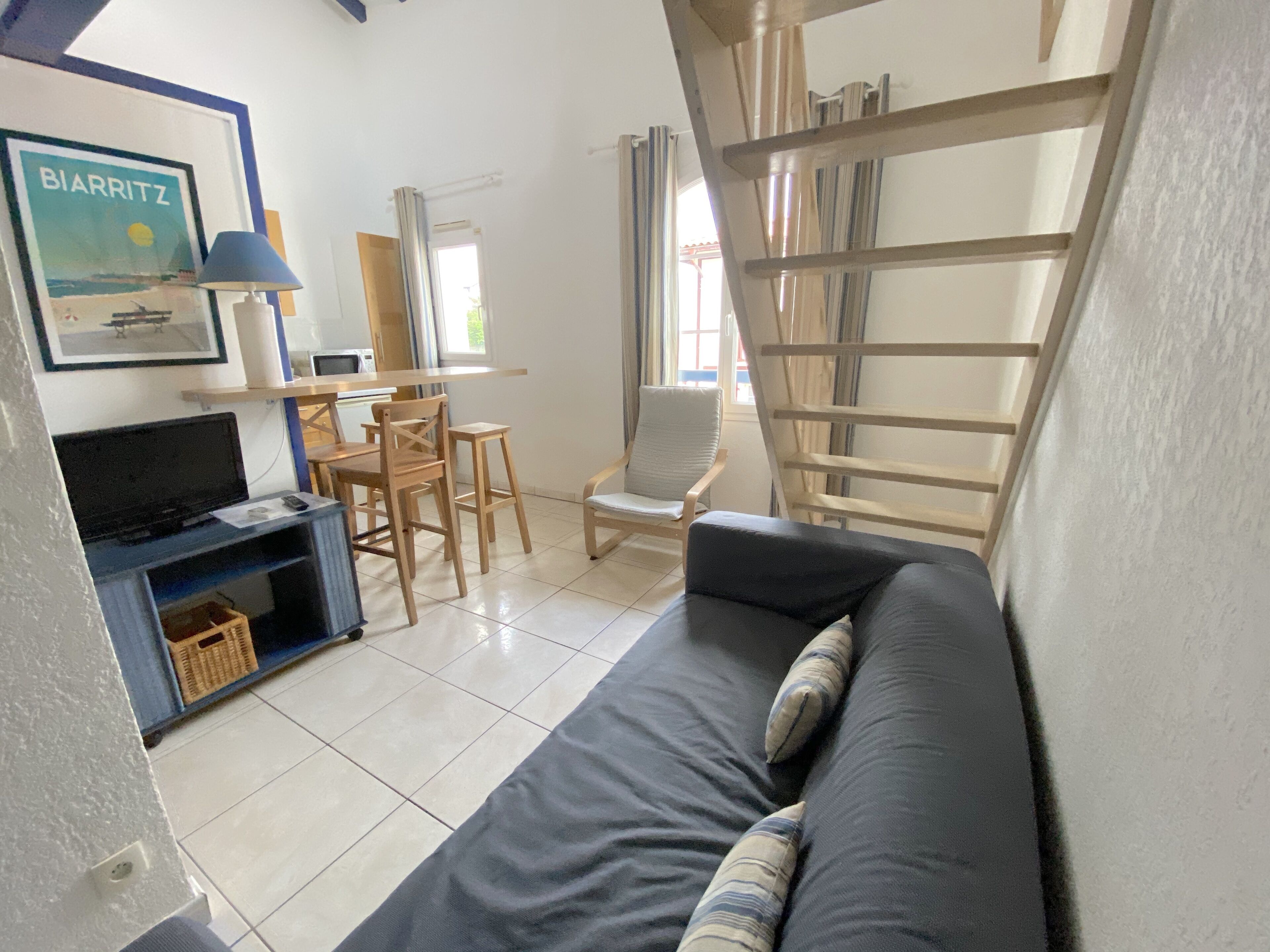 A living room with a sofa, a TV, a wooden chair, and a table.
