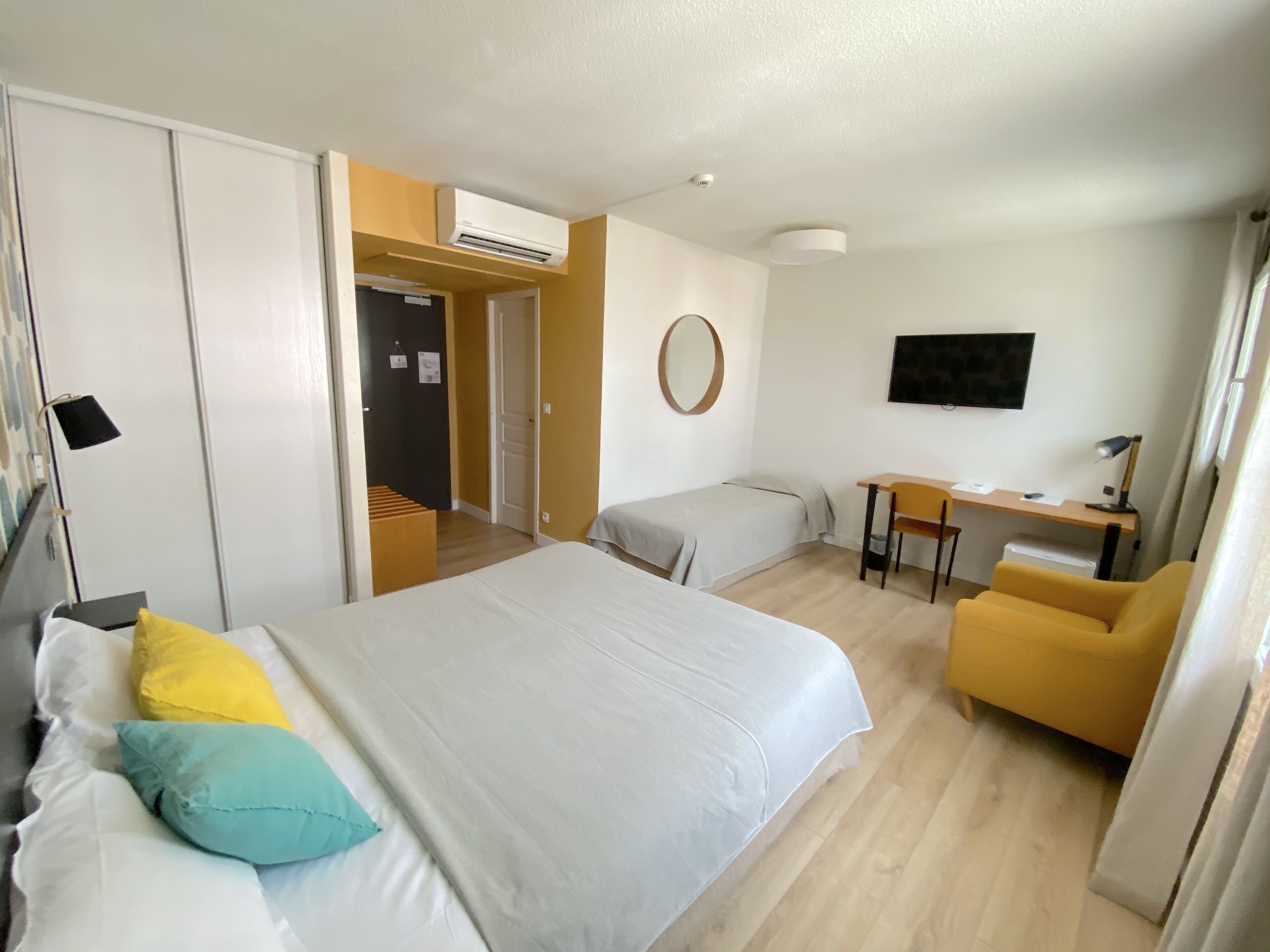 A hotel room with a bed, a desk, a chair, and a TV.