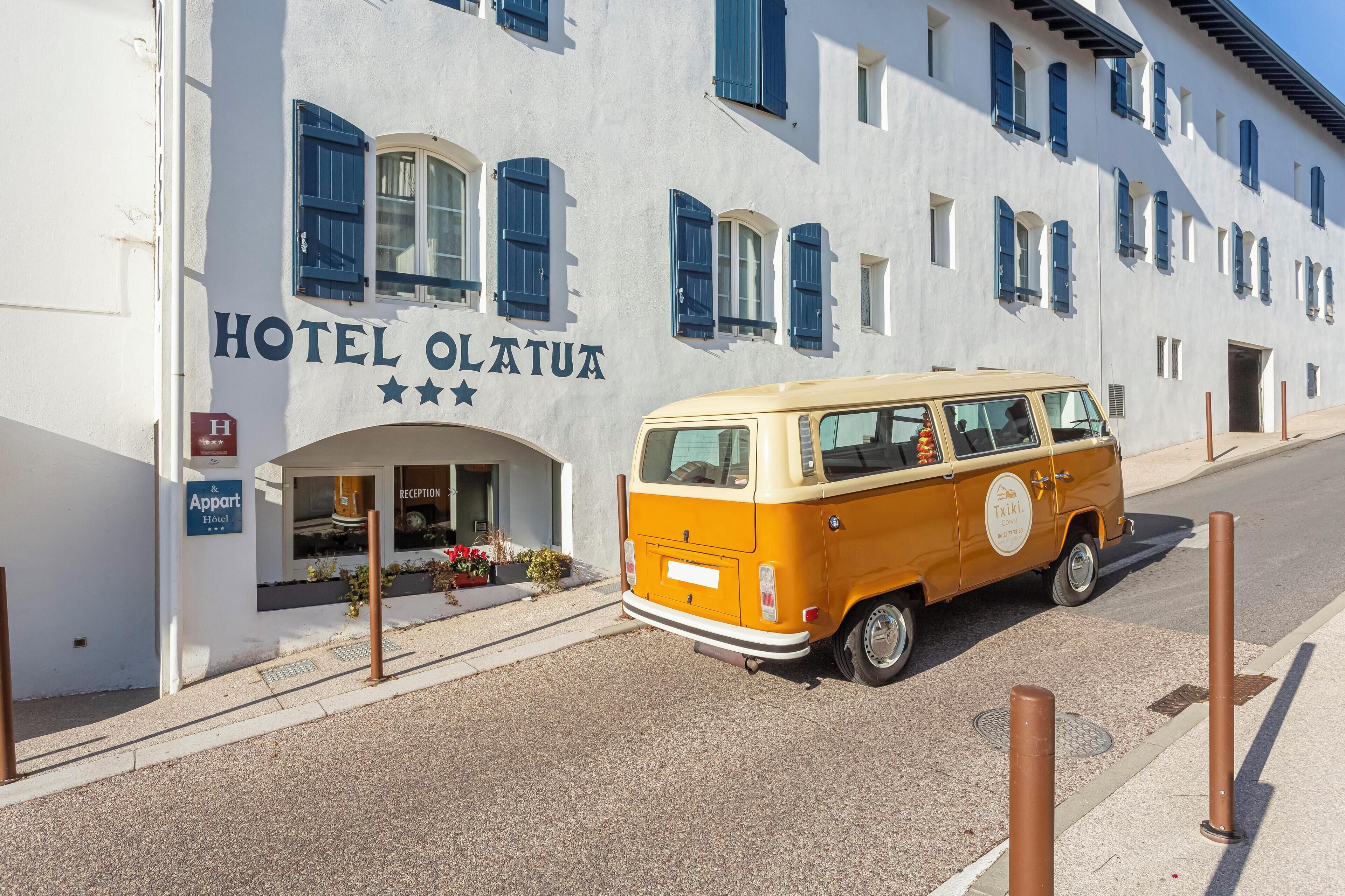 A vintage yellow van parked in front of Hotel Olatu.