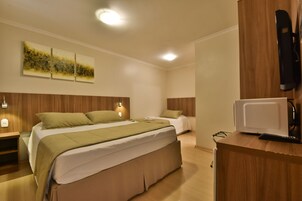 Camera d'albergo moderna con un letto grande, un letto più piccolo, una scrivania con forno a microonde e una TV a parete.