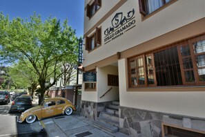 Un edificio con un letrero que dice "Stilio Gramado" y un coche antiguo estacionado afuera.
