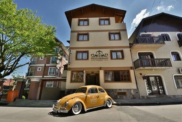 Un edificio de varios pisos en color beige con un letrero que dice "Stillo Gramado Pousada".